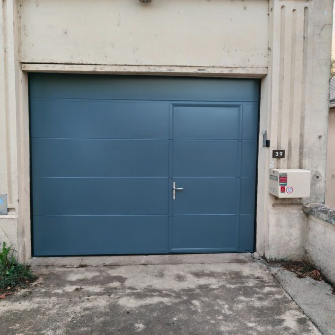 Porte de garage sectionnelle gris bleu avec portillon intégré, installée par Octopus Habitat à Saumur.